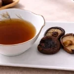 Cuenco lleno de caldo dashi vegano con varias setas shiitake.
